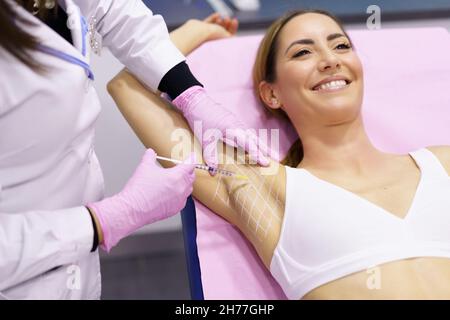 Le médecin effectue des injections intramusculaires de toxine botulinique dans la zone des aisselles contre l'hyperhidrose. Banque D'Images