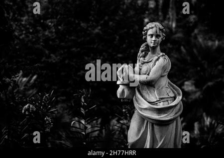 Photo en niveaux de gris d'une magnifique statue de femme dans un parc. Banque D'Images