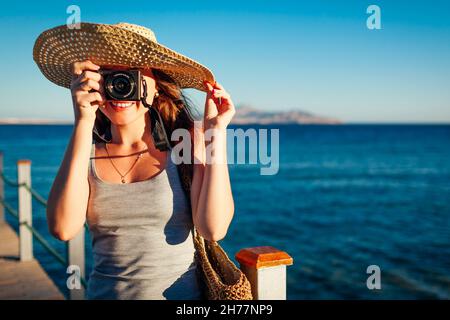 Bonne jeune femme voyageur prenant des photos de paysage de mer sur la jetée à l'aide de l'appareil photo.Vacances d'été en Egypte.Tourisme à Charm el-Cheikh Banque D'Images