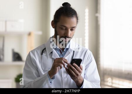 Gros plan Afro-américain homme médecin utilisant un smartphone à l'hôpital Banque D'Images