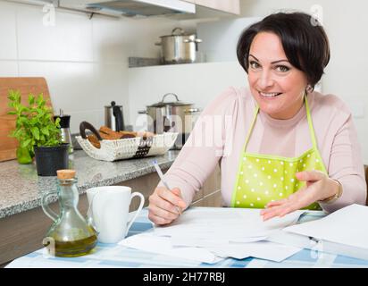 Femme heureuse avec application bancaire dans la cuisine Banque D'Images