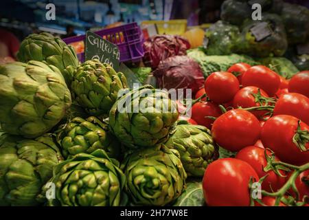 Gros plan d'artichauts verts et de tomates rouges en vente sur le marché, Barcelone, Espagne, Europe Banque D'Images