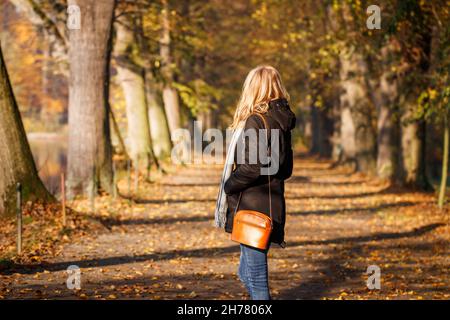 Femme nerveuse attendant quelqu'un dans une ruelle dans un parc d'automne.Mode de vie à l'automne Banque D'Images