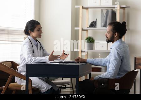 Femme indienne souriante médecin parlant, consultant un patient afro-américain Banque D'Images