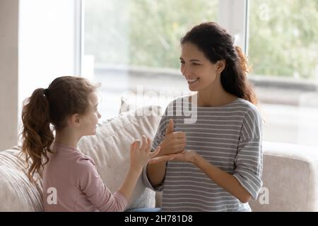 Souriante mère d'accueil enseignant fille handicapée, apprentissage signe geste Banque D'Images