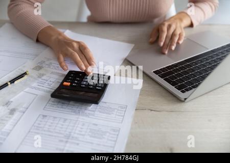 Gros plan femme calculant des factures, à l'aide d'une calculatrice et d'un ordinateur portable Banque D'Images