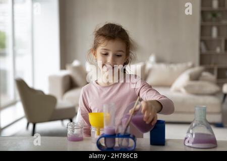 Curieux souriant petite fille jouant avec le laboratoire de jouets, expériences de chimie Banque D'Images