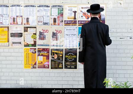 Un juif hassidique anonyme lit des annonces et des publicités sur un mur à Williamsburg Brooklyn, New York. Banque D'Images