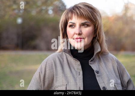 Une belle femme mûre aux courbes regarde sur le côté.Portrait féminin d'une personne d'âge moyen à l'extérieur Banque D'Images
