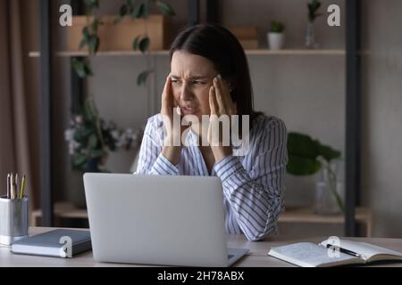 Jeune femme d'affaires malsaine ayant de forts maux de tête sur le lieu de travail. Banque D'Images