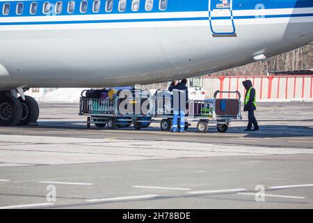 chargement des bagages à l'aéroport en hiver. Bagages dans les chariots près de l'avion en hiver. Avion passager en hiver à l'aéroport a chargé des bagages avant le départ Banque D'Images