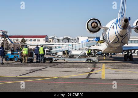 chargement des bagages à l'aéroport en hiver. Bagages dans les chariots près de l'avion en hiver. Avion passager en hiver à l'aéroport a chargé des bagages avant le départ Banque D'Images