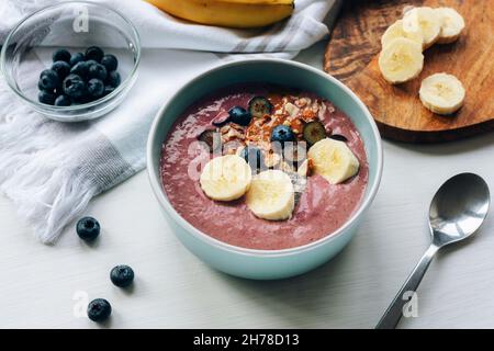 Bol lisse avec banane, graines de chia, bleuets, noix et beurre d'arachide.Petit déjeuner végétalien sain.Vue de dessus. Banque D'Images