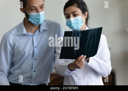 Médecin indien en masque médical tenant des rayons X, consultant le patient Banque D'Images