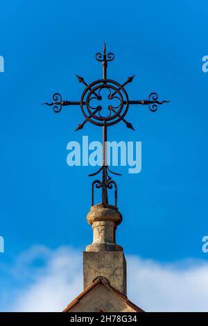 Détail d'une croix en fer forgé sur un ciel bleu avec des nuages, symbole religieux chrétien.Église du Sacré-cœur à la Spezia, Ligurie, Italie. Banque D'Images