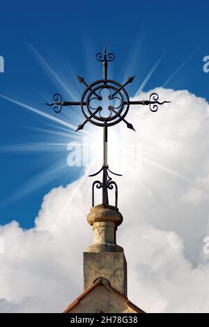 Croix de fer forgé sur un ciel bleu avec des nuages et des rayons de soleil, symbole religieux chrétien.Église du Sacré-cœur à la Spezia, Ligurie, Italie Banque D'Images