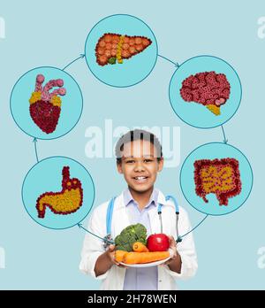 Enfants concept de nutrition saine.Un garçon afro-américain portant l'uniforme du médecin avec des légumes et des fruits sains recommande la nourriture naturelle pour l'enfant Banque D'Images