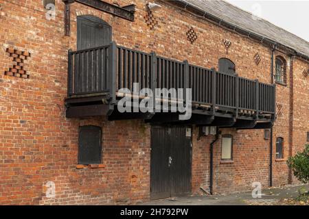Balcon peint en noir contre un mur de briques rouges sur un ancien bâtiment de grange Banque D'Images