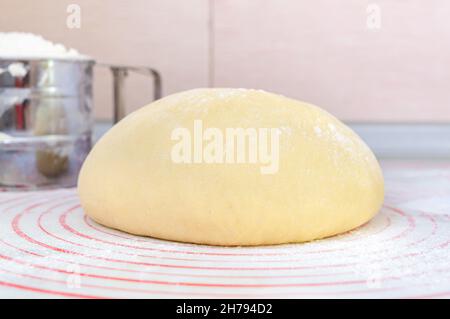 Pâte à lever crue sur un tapis spécial en silicone pour rouler la pâte sur la table de cuisine.Préparation de pâte pour pizza, tarte, pâtisserie et autre boulangerie Banque D'Images