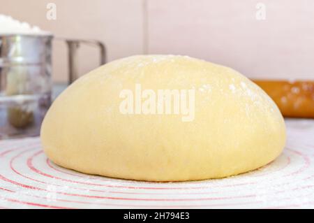 Pâte à lever crue sur un tapis spécial en silicone pour rouler la pâte sur la table de cuisine.Préparation de pâte pour pizza, tarte, pâtisserie et autre boulangerie Banque D'Images