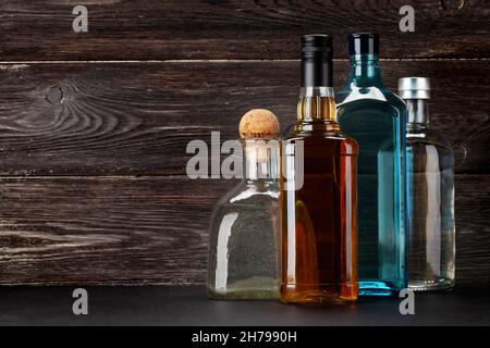 Plusieurs bouteilles de liqueur dure.Gin, vodka, tequila et whisky devant un mur en bois avec espace de copie Banque D'Images