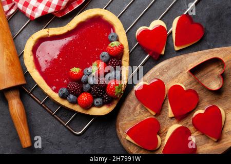 Gâteau sucré en forme de coeur avec baies et biscuits en forme de coeur.Carte de voeux pour la Saint-Valentin.Plan d'étapage avec vue de dessus Banque D'Images