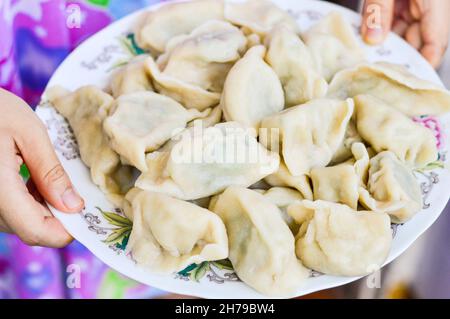 Deux mains tenant une assiette de boulettes chinoises bouillies (Jiaozi) Banque D'Images