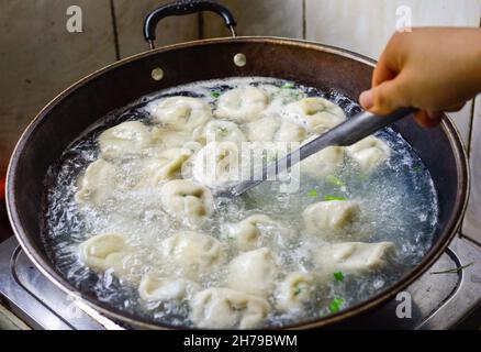 Une famille chinoise cuisant les boulettes dans un wok. Banque D'Images