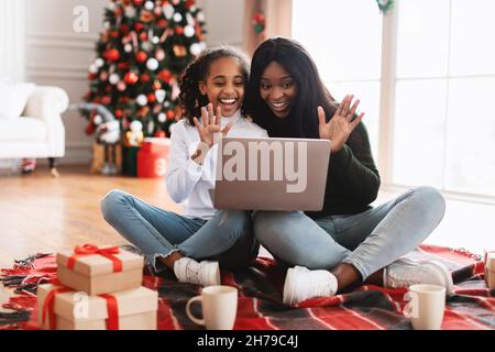 Famille noire utilisant un pc pour réaliser un jeu vidéo sur Noël en se faisant passer les mains Banque D'Images