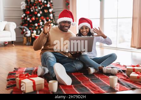 Famille noire utilisant un pc pour réaliser un jeu vidéo sur Noël en se faisant passer les mains Banque D'Images