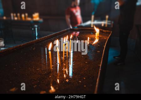 Beaucoup de bougies brûlent dans une église catholique médiévale sombre et des rayons de lumière passent par une fenêtre étroite.Le concept de foi et de rel Banque D'Images