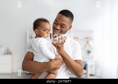 Les technologies modernes et les bébés.Père tenant bébé enfant et parlant sur Haut-parleur Banque D'Images