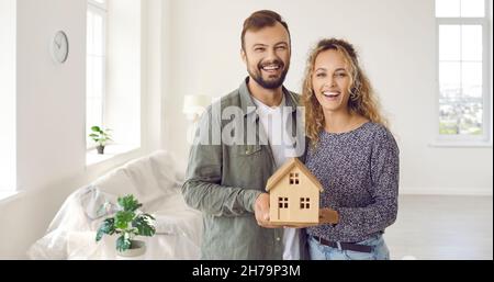 Bannière avec un jeune couple heureux qui ont acheté une nouvelle maison tenant petit modèle de maison Banque D'Images