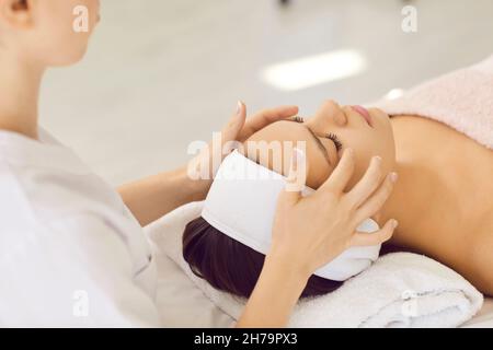 La femme au spa reçoit un massage de la tête et du visage de la masseuse professionnelle féminine. Banque D'Images