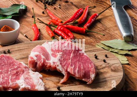 Deux steak cru au piment de Cayenne, poivre en poudre, et d'autres condiments Banque D'Images