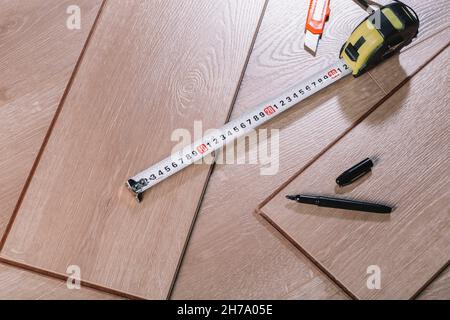 Installation de revêtements de sol stratifiés dans une salle ou un bureau.Parquet et outils.Travaux de construction et de décoration pour la finition de logements.Photo de haute qualité Banque D'Images