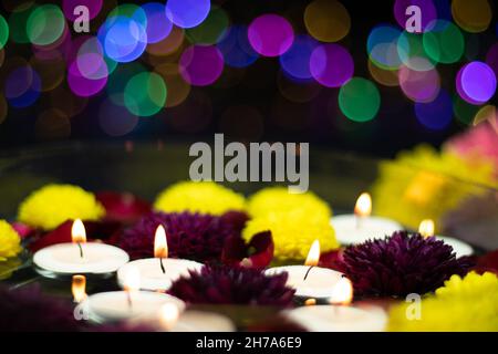 Bougies chauffe-plat flottantes illuminées par des fleurs jaunes et marron multicolores fraîches.Bokeh coloré sur fond sombre.Thème pour Shubh Banque D'Images