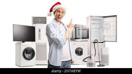 Jeune homme heureux avec un chapeau de père noël pointant vers des appareils domestiques isolés sur fond blanc Banque D'Images