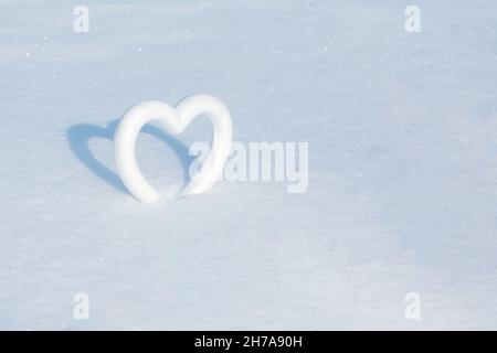 Symbole coeur en polystyrène sur la neige blanche étincelante au soleil.La base de la carte postale.Place pour une inscription. Banque D'Images