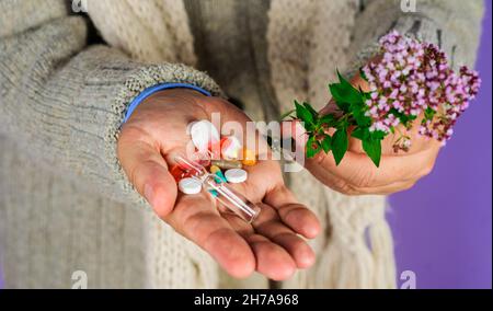 Main d'homme avec des pilules et des plantes.Herbes naturelles.Homéopathie, naturopathie.Médecine alternative. Banque D'Images