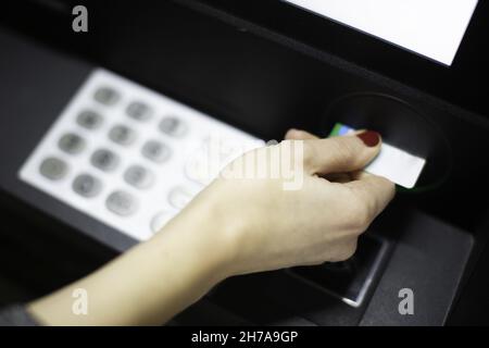 Une main féminine insérant une carte de crédit dans un guichet automatique Banque D'Images