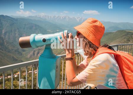 Une femme sur la terrasse d'observation regarde à travers le télescope touristique vers les montagnes ou l'observation des oiseaux.Concept de voyage et de tourisme Banque D'Images