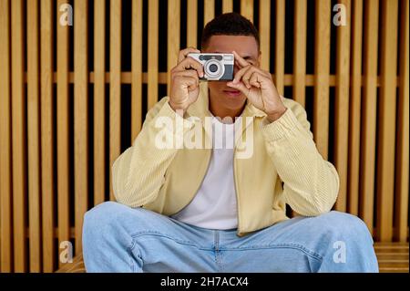 Photographe masculin assis et tenant l'appareil photo entre les mains Banque D'Images