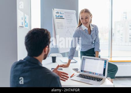 Une femme est venue à un collègue, s'est assise sur son bureau et lui a parlé avec joie. Banque D'Images