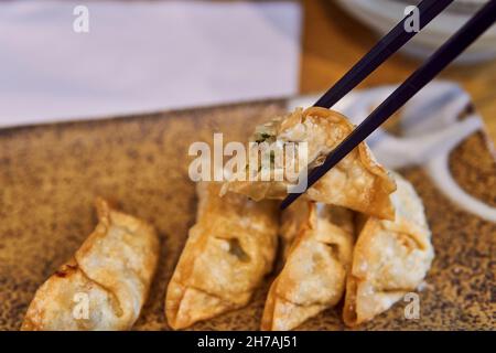 Vegan gyoza dans la moitié entre une paire de baguettes. Banque D'Images