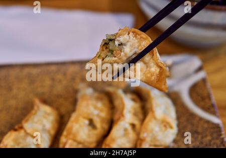 Vegan gyoza dans la moitié entre une paire de baguettes. Banque D'Images