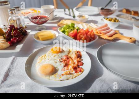 œufs frits avec des tranches de bacon juteux et gras sur une assiette pendant le petit déjeuner dans un café ou à la maison Banque D'Images