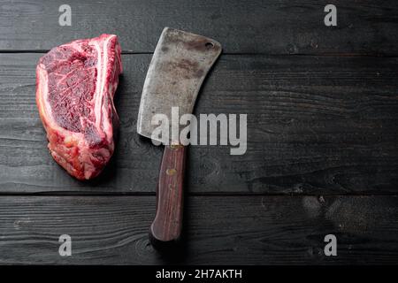 Set de steak Club vieilli à base de viande fraîche brute, sur fond de table en bois noir, avec espace pour le texte Banque D'Images