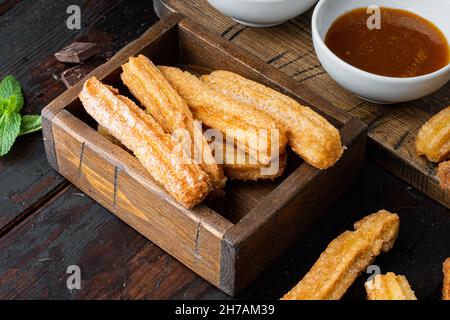 Churros arrosé de sucre en poudre, sur fond de table en bois foncé Banque D'Images