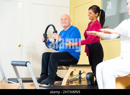 Femme hispanique entraîneur de forme physique contrôle homme âgé s'exerçant avec Magic Circle Banque D'Images